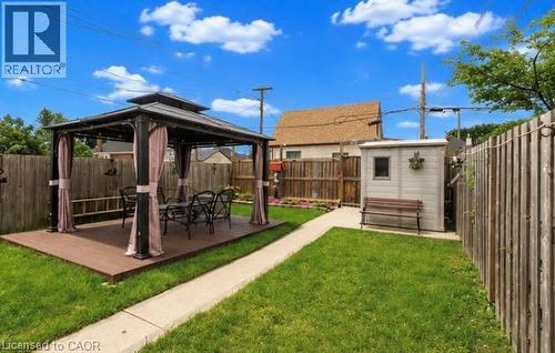 Expansive backyard featuring a composite deck with a metal gazebo, a concrete pathway, a storage shed, and wooden fencing - 237 Paling Avenue, Hamilton, ON - Outdoor