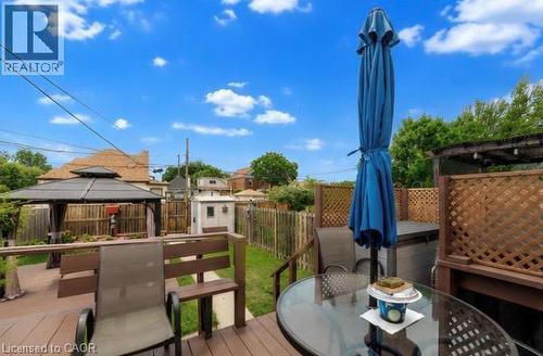 Expansive wood-finish deck featuring a privacy lattice, built-in bench seating, and a gazebo with drapes - 237 Paling Avenue, Hamilton, ON - Outdoor With Deck Patio Veranda