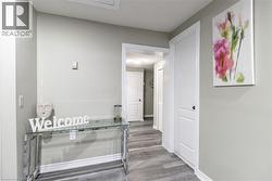 Interior hallway with wood-finish flooring, light grey wall paint, and white trim - 