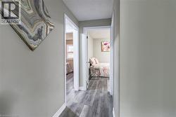 Hallway featuring wood-finish flooring, light gray wall paint, and white trim - 