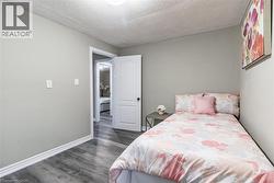 Bedroom featuring wood-finish flooring, light gray wall paint, and white baseboards - 