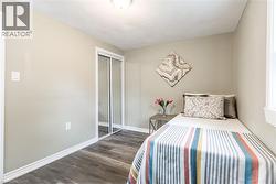 Interior room featuring wood-finish flooring, light neutral wall paint, and white baseboards - 