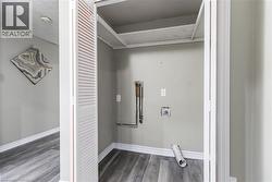 Dedicated laundry closet featuring louvered bi-fold doors, wood-finish flooring, and light gray walls - 