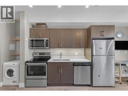 Modern kitchen featuring quartz countertops, stainless steel appliances, sleek pot lights, and under-cabinet task lighting - 