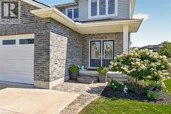 Contemporary exterior featuring a gray brick facade, double entry doors, covered porch, concrete driveway, and a white panel garage door - 