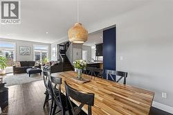 Dining area featuring a butcher block-style table, a woven pendant light, and dark wood-finish flooring - 