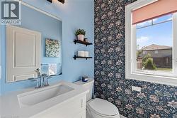 Bathroom featuring a white vanity with an integrated sink, polished chrome faucet, rectangular mirror, and a wallpaper accent wall - 