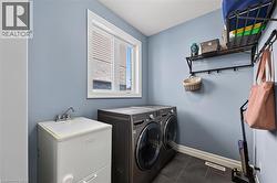 Dedicated laundry area featuring a utility sink, dark tile flooring, and a window with white trim - 