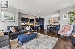 Open-concept living space featuring wood-finish flooring throughout, recessed ceiling lighting, and a neutral wall color - 