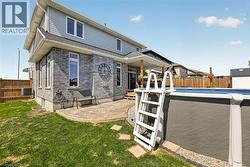 Backyard featuring an above-ground pool, a concrete patio, and a covered deck - 