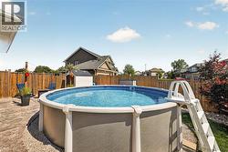 Above-ground swimming pool with an exterior ladder, surrounded by a stamped concrete patio and gravel landscaping - 