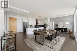 Virtually staged. Open-concept living space featuring wood-finish flooring, recessed lighting, and a modern kitchen with white cabinetry and stainless steel appliances - 