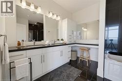 Virtually staged. Bathroom featuring a dual vanity with undermount sinks, sleek black countertops, and extensive white cabinetry - 