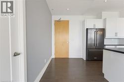 Modern kitchen featuring white cabinetry, a stainless steel French door refrigerator, white subway tile backsplash, and dark countertops - 
