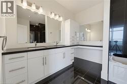 Dual vanity with undermount sinks, dark countertops, and white cabinetry - 