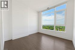 Expansive window offering a broad landscape, wood-finish flooring, recessed ceiling lighting, clean white walls, and substantial baseboards - 
