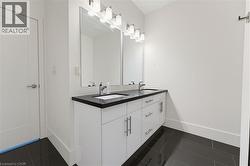 Bathroom with a double vanity featuring a dark countertop, undermount sinks, and chrome faucets - 