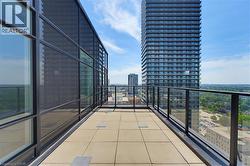 Expansive outdoor terrace featuring paver flooring, modern glass railings, and a full-height window wall - 