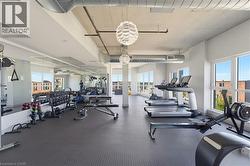 Fitness center with large windows, exposed ceiling ducts, industrial lighting, mirror wall, and dark rubber flooring - 