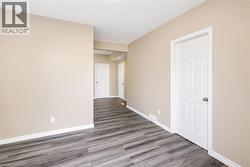 Interior space featuring neutral wall paint, wood-finish flooring, white baseboards, and white paneled doors - 
