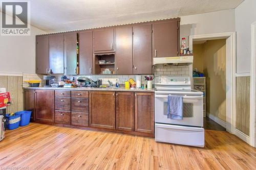 Kitchen featuring wood-finish flooring, subway tile backsplash, and extensive cabinetry - 819 Duke Street, Cambridge, ON - Indoor Photo Showing Kitchen