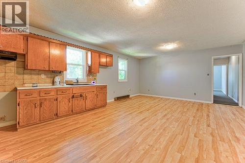 Kitchen and living area featuring wood-finish flooring, oak cabinetry, and light gray walls - 819 Duke Street, Cambridge, ON - Indoor Photo Showing Kitchen
