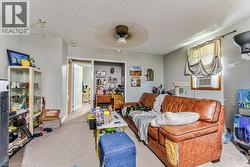 Carpeted interior space with light gray walls, a ceiling fan, and a window with an air conditioning unit - 