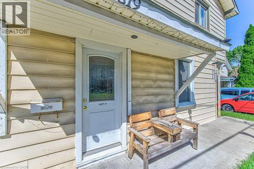 Exterior entrance featuring a light-colored door with an arched glass insert, horizontal siding, and a covered porch area - 819 Duke Street, Cambridge, ON - Outdoor