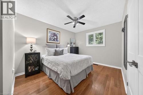 Bedroom featuring wood-finish flooring, a ceiling fan with integrated lighting, and a window with plantation shutters - 30 Carriagegate Drive, Hamilton, ON - Indoor Photo Showing Bedroom