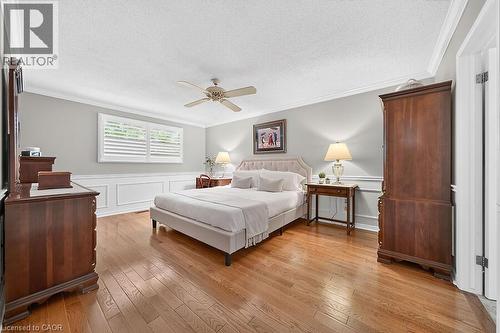 Spacious room featuring hardwood flooring, extensive crown molding, wainscoting, and a ceiling fan - 30 Carriagegate Drive, Hamilton, ON - Indoor Photo Showing Bedroom