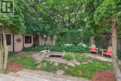 Landscaped backyard featuring a stone fire pit, stepping stone pathway, and mature trees providing natural canopy - 30 Carriagegate Drive, Hamilton, ON - Outdoor