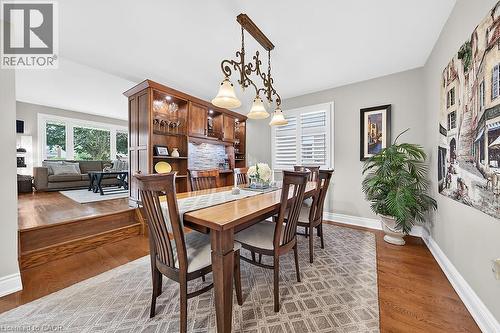 Formal dining area featuring rich wood-finish flooring, a decorative chandelier, and a built-in wood-finish display cabinet with integrated lighting and a stone-tile backsplash - 30 Carriagegate Drive, Hamilton, ON - Indoor Photo Showing Dining Room