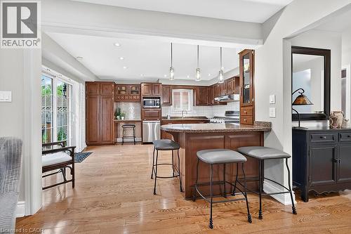 Open-concept kitchen featuring wood-finish flooring, recessed lighting, and a breakfast bar with stone-finish countertops - 30 Carriagegate Drive, Hamilton, ON - Indoor Photo Showing Kitchen