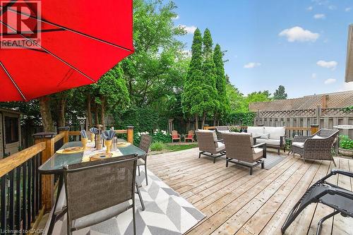 Expansive wooden deck featuring multiple outdoor seating areas, a privacy fence, and mature perimeter trees - 30 Carriagegate Drive, Hamilton, ON - Outdoor With Deck Patio Veranda With Exterior
