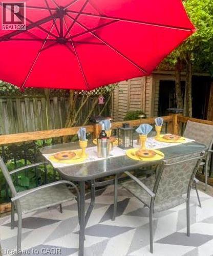 Outdoor patio featuring a geometric patterned floor, wood railing, and a storage shed in the background - 30 Carriagegate Drive, Hamilton, ON - Outdoor With Deck Patio Veranda