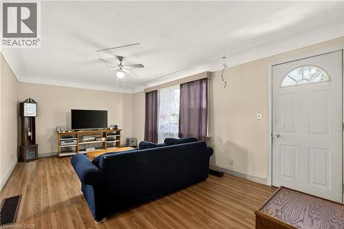 Living area featuring wood-finish flooring, a ceiling fan with integrated lighting, and crown molding - 958 Highland Road E, Hamilton, ON 