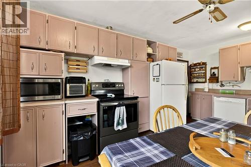 Kitchen featuring extensive cabinetry, white appliances, and a ceiling fan - 958 Highland Road E, Hamilton, ON 