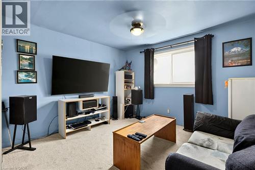 Carpeted room featuring a ceiling-mounted light fixture, a window with dark curtains, and light blue walls - 958 Highland Road E, Hamilton, ON 