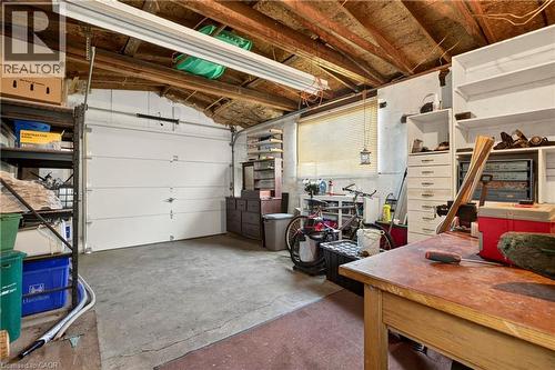 Garage space featuring a concrete floor, exposed wood beam ceiling, and a white overhead door - 958 Highland Road E, Hamilton, ON 