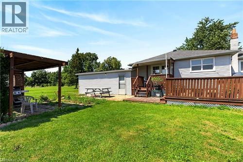 Expansive green lawn with a covered pergola, separate utility building, and a wood-decked patio with protective railing - 958 Highland Road E, Hamilton, ON 