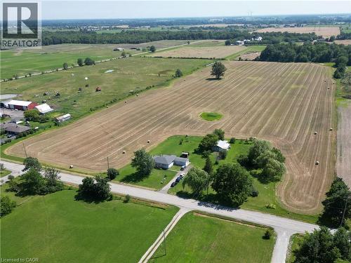 Expansive rural property featuring a white single-story residence, multiple outbuildings, mature trees, and agricultural fields - 958 Highland Road E, Hamilton, ON 