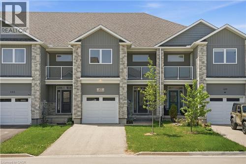 Modern townhome exterior featuring stone veneer accents and vertical siding - 107 Stephenson Way, Palmerston, ON - Outdoor With Balcony With Facade