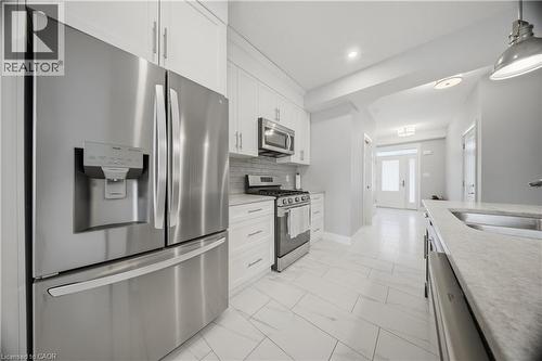 Contemporary kitchen featuring stainless steel appliances, white cabinetry, light countertops, and large format floor tiling - 107 Stephenson Way, Palmerston, ON - Indoor Photo Showing Kitchen With Stainless Steel Kitchen With Upgraded Kitchen