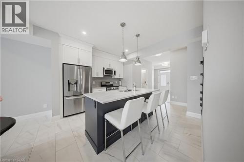 Modern kitchen featuring a central island with seating, white shaker-style cabinetry, stainless steel appliances, and a light-toned tiled floor - 107 Stephenson Way, Palmerston, ON - Indoor Photo Showing Kitchen With Stainless Steel Kitchen With Upgraded Kitchen