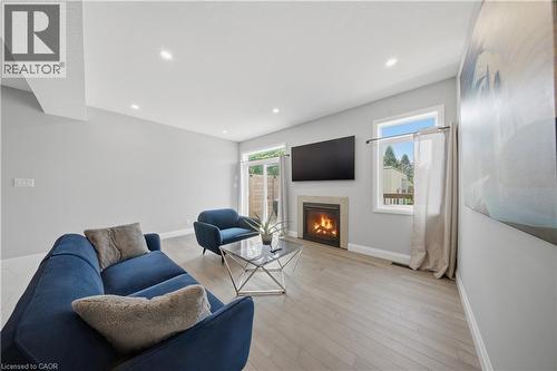 Living area featuring a stone surround fireplace with a built-in mantel, recessed lighting, and wood-finish flooring - 107 Stephenson Way, Palmerston, ON - Indoor Photo Showing Living Room With Fireplace