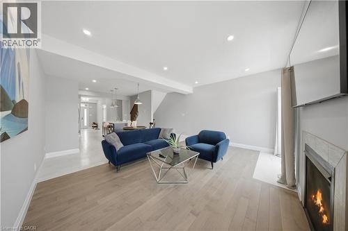 Open-concept living area featuring wood-finish flooring, recessed lighting, and a modern fireplace with a tiled surround - 107 Stephenson Way, Palmerston, ON - Indoor Photo Showing Living Room With Fireplace