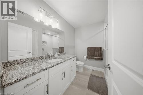 Double vanity with integrated sinks, speckled stone countertops, and ample white cabinetry - 107 Stephenson Way, Palmerston, ON - Indoor Photo Showing Bathroom