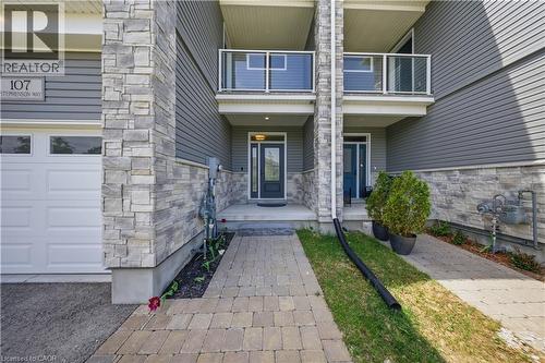 Stone and siding exterior with a garage door and paved walkway - 107 Stephenson Way, Palmerston, ON - Outdoor With Balcony