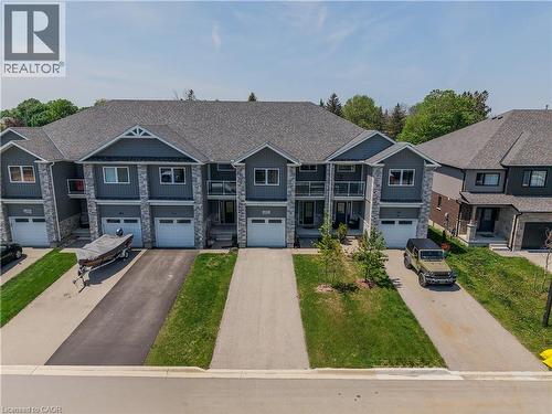 Modern townhome exterior with mixed material siding, stone accents, and a grey shingle roof - 107 Stephenson Way, Palmerston, ON - Outdoor With Facade