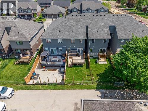 Rear exterior featuring a spacious deck with a pergola, a gravel patio with a built-in fire pit, and a fenced yard - 107 Stephenson Way, Palmerston, ON - Outdoor With Deck Patio Veranda